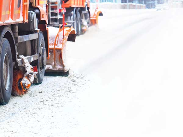 Mechanized snow removal. Blurred winter background. Snow plough truck clearing road after blizzard from street. Snow plows, snowstorm. Space for text