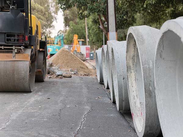 Steam roller parked near storm water pipes