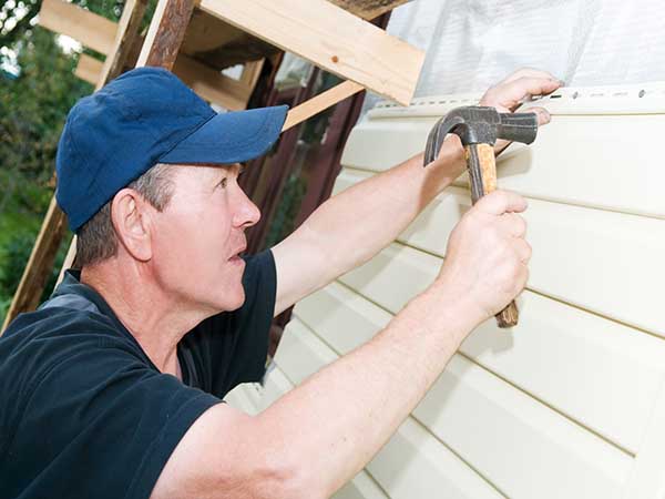 Worker planking house with plastic siding panels